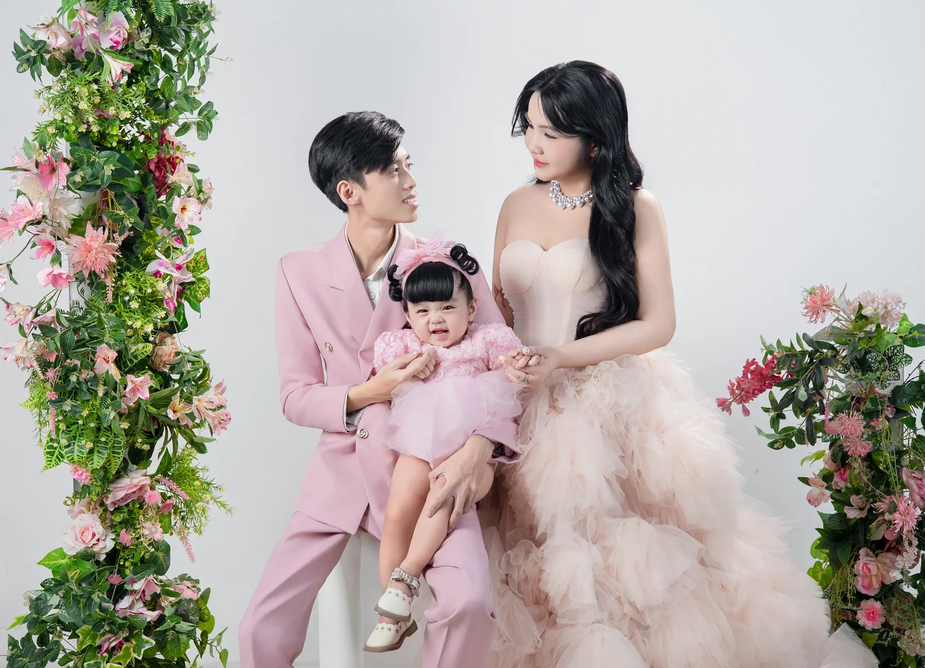 Bố mẹ và bé chụp cạnh khung hoa hồng